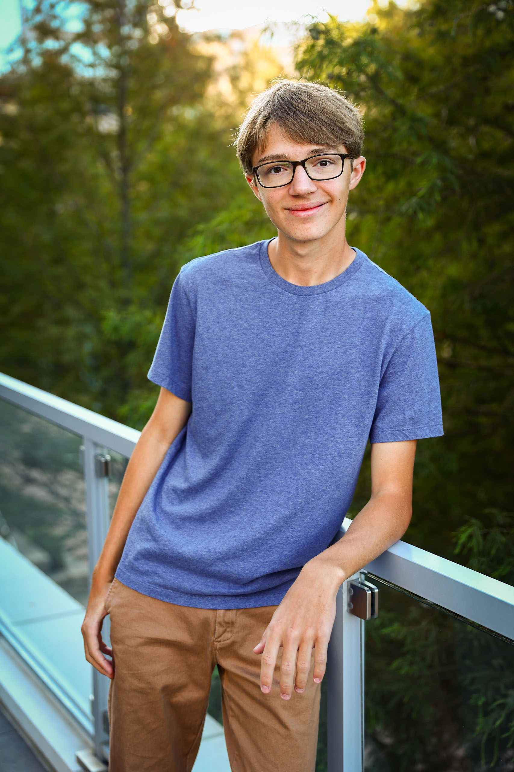High school senior boy leaning on railing.